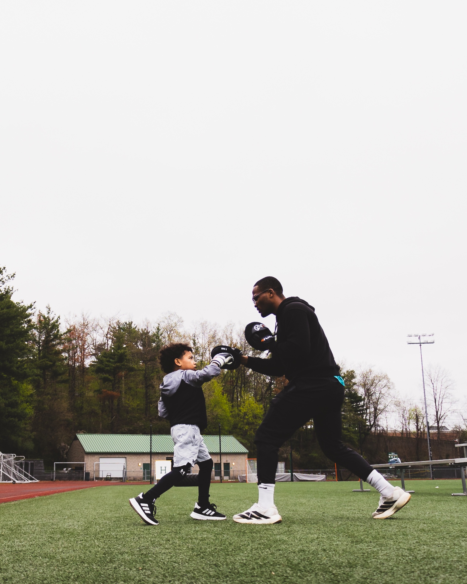 Coach Josh training a young boxer outdoors on the Hamden High track