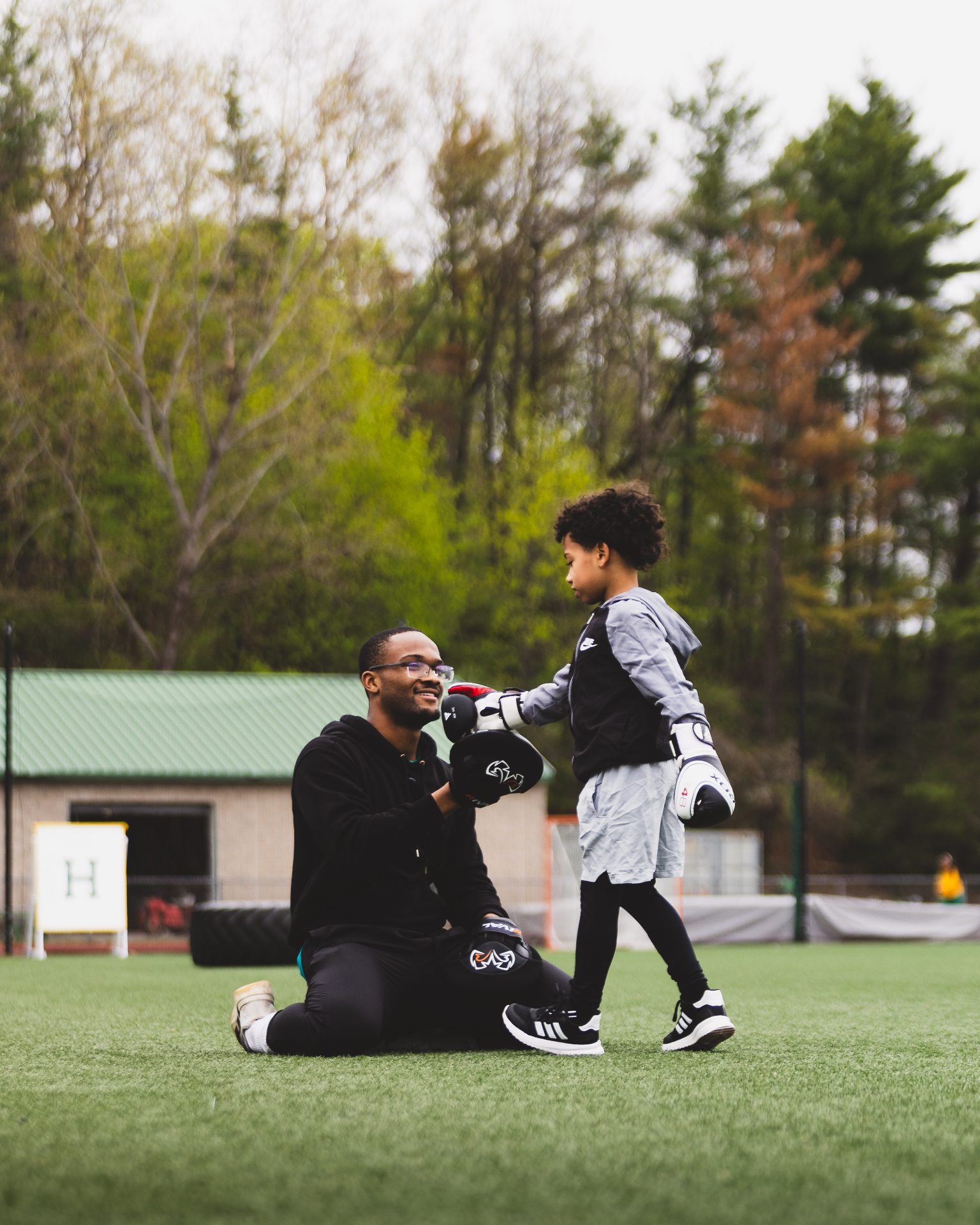 Young boxer hitting mitts with Coach Josh outdoors